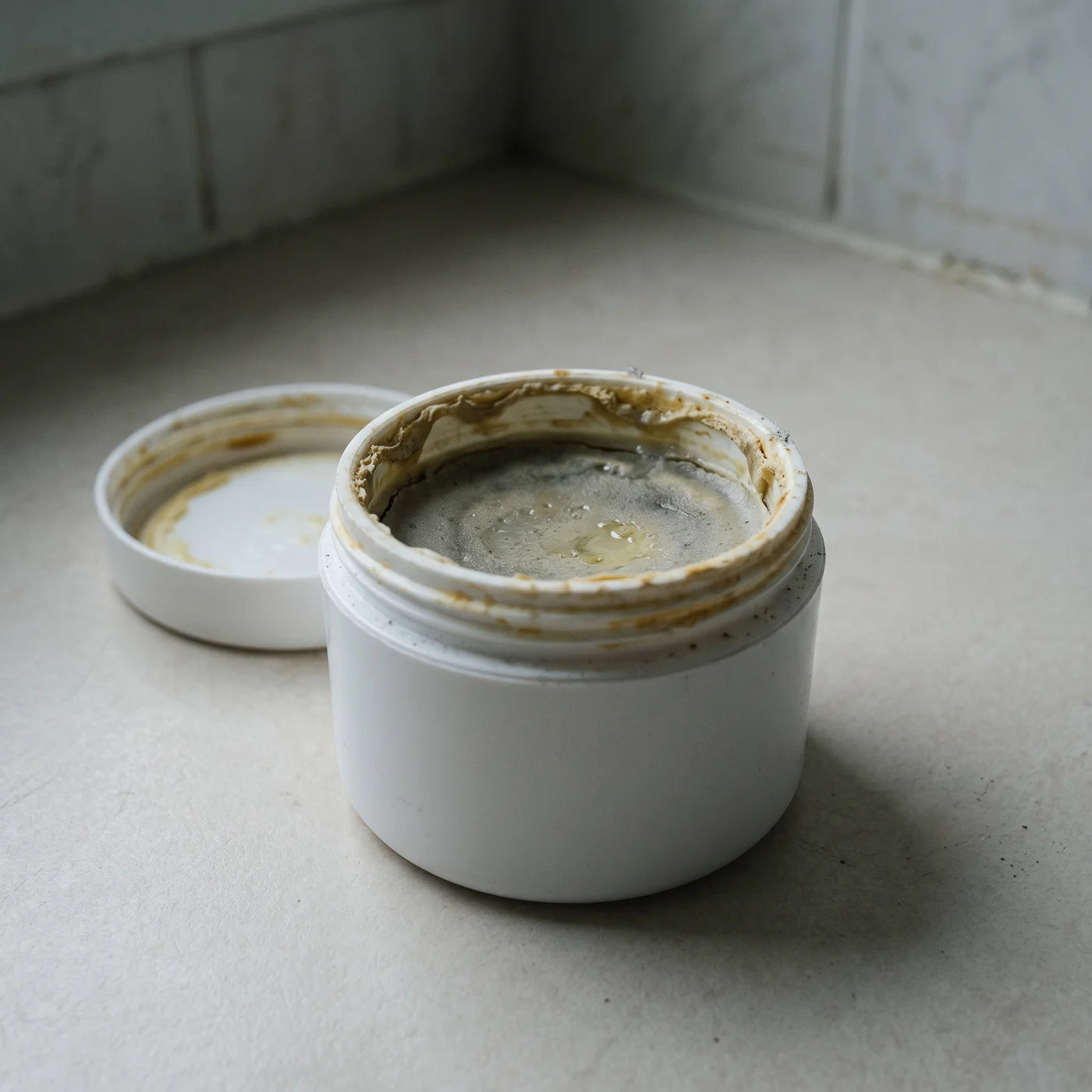 Tarro de crema convencional abierto, con la superficie ya oscurecida por la oxidación
